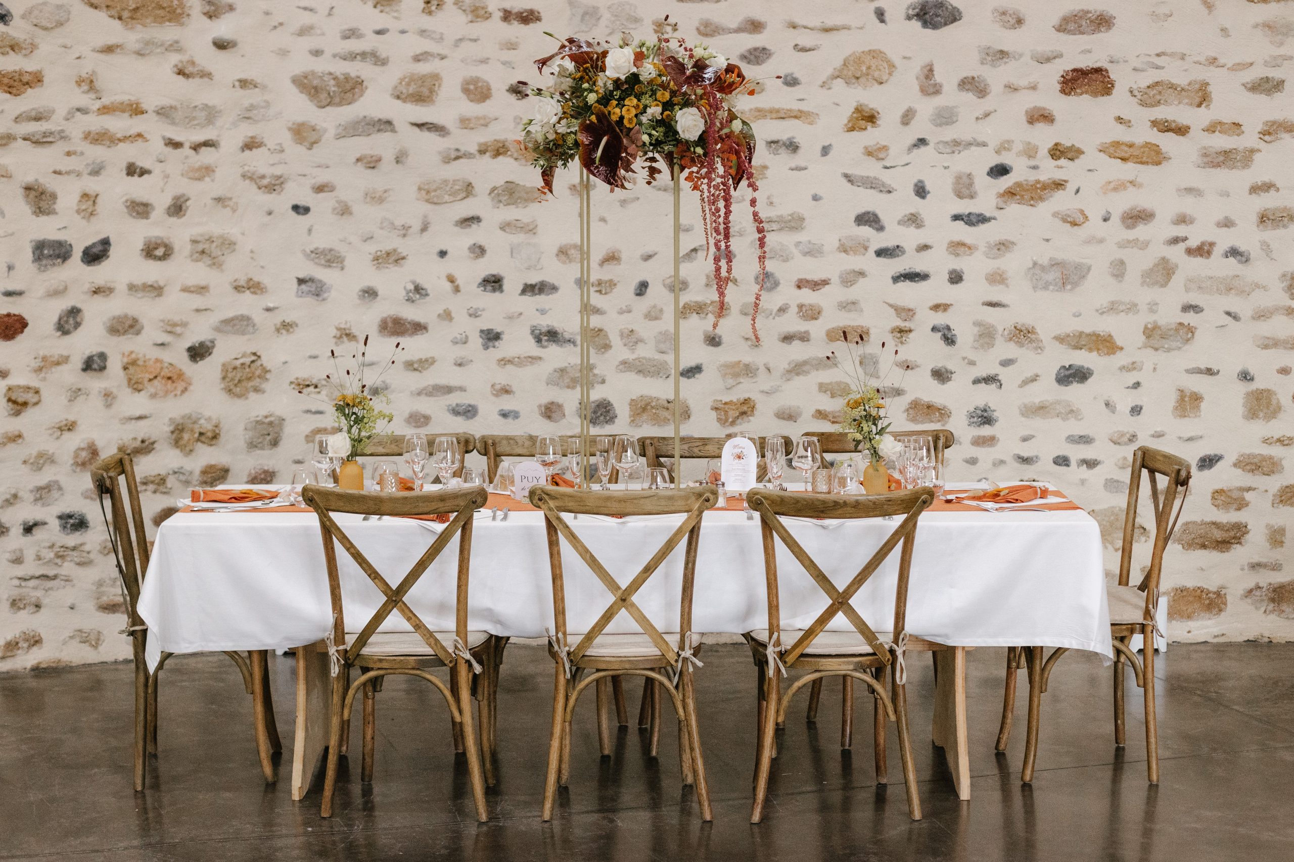 Table d'honneur mariage avec arrangement floral sur pied doré et chaises champêtres