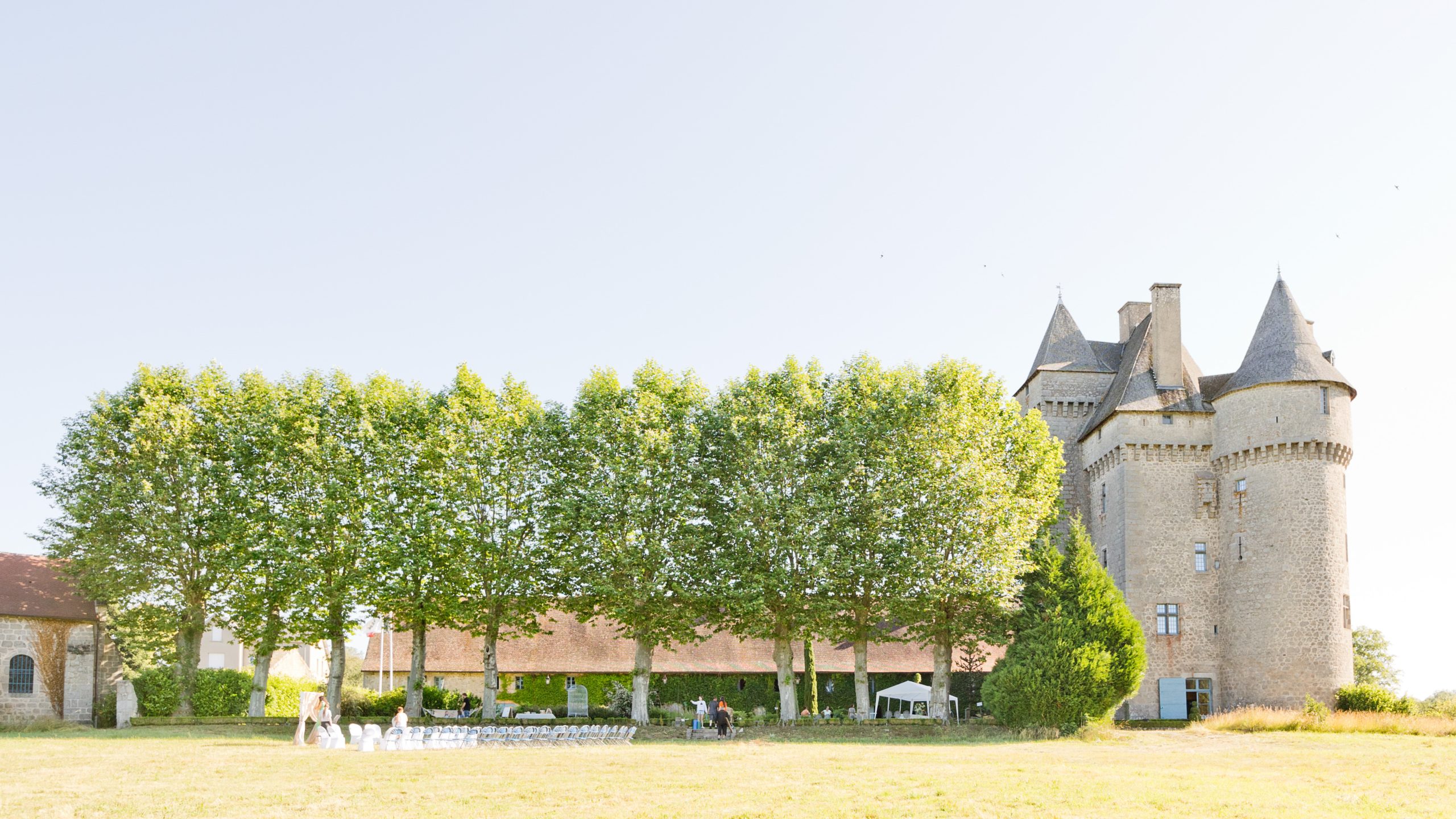 Château de Saint-Maixant en Creuse avec sa tour médiévale, allée de tilleuls et chaises de cérémonie installées sur la pelouse